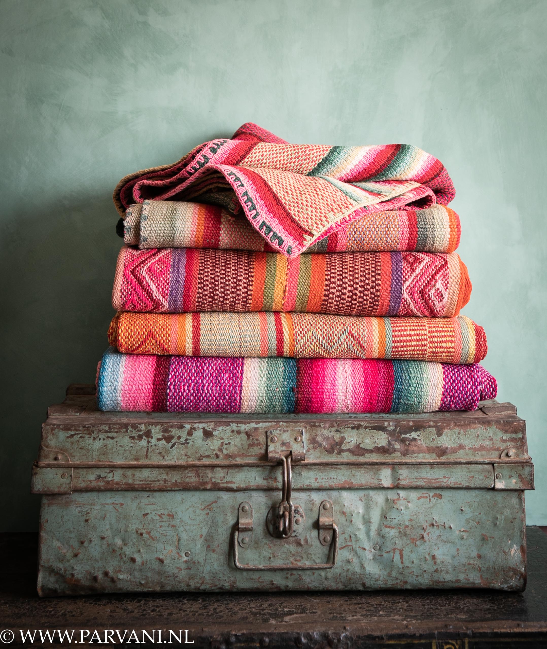 oude ijzeren koffer met vrolijke fel gekleurde frazada plaids en dekens met patronen en strepen