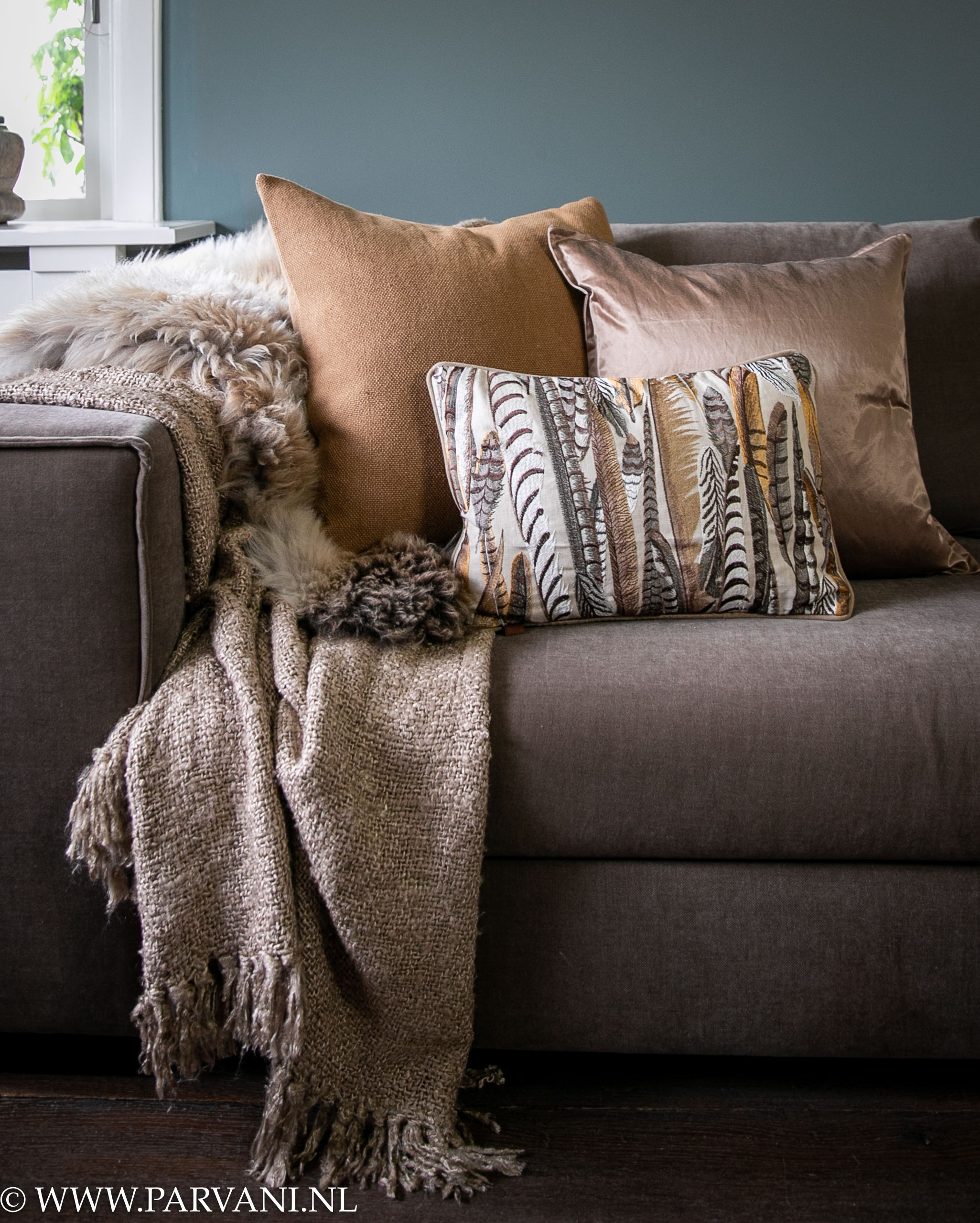 Grof gehaakt plaid met schapenvacht en sierkussens in bruine terra tinten