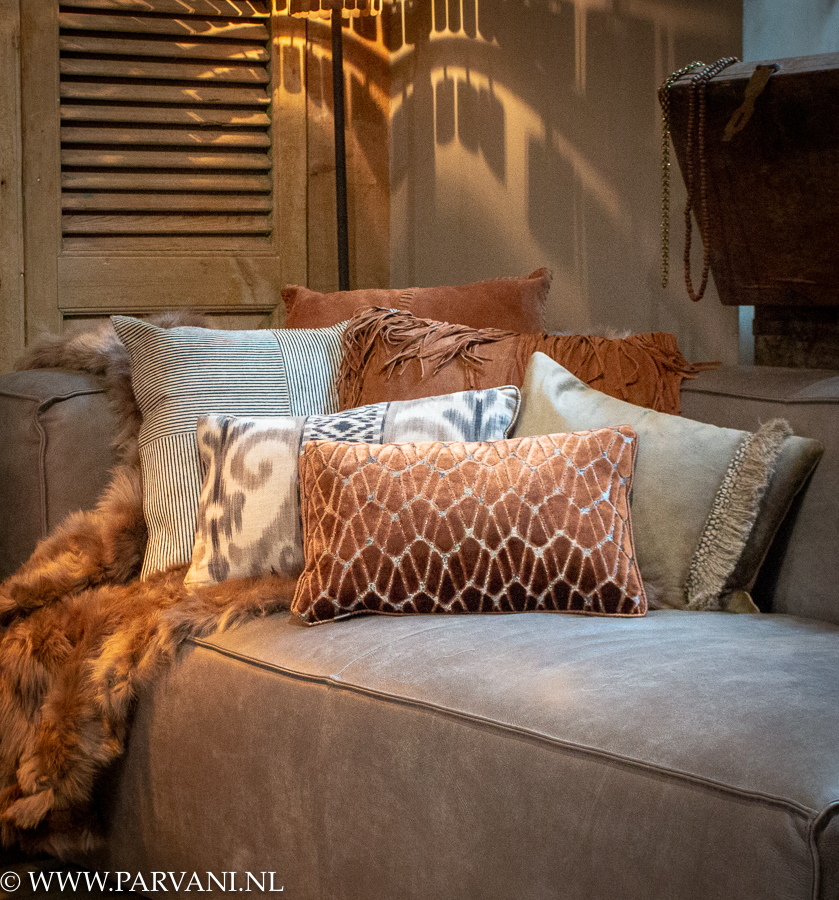 Kussens en plaid op bank in warme cognac rood bruine kleuren