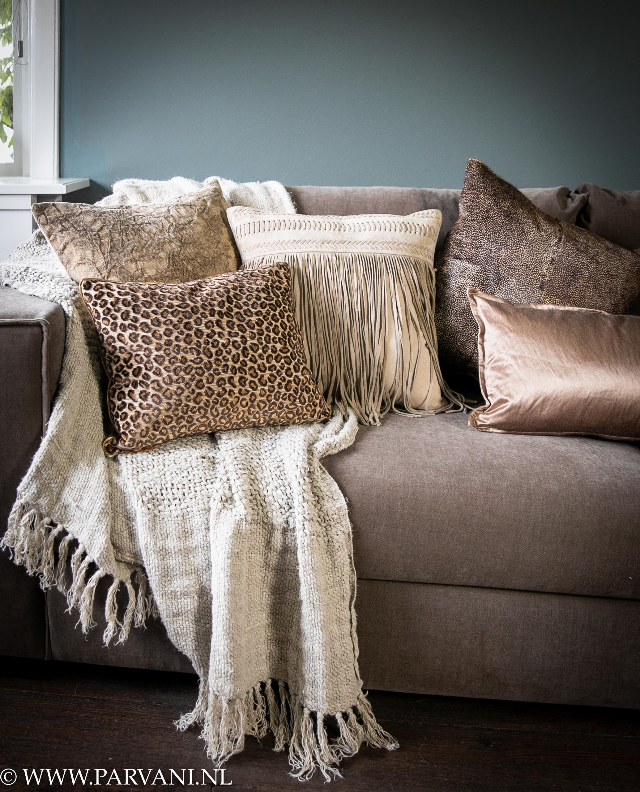 Kussens op bank in warme bruin beige kleuren met naturel grof linnen plaid