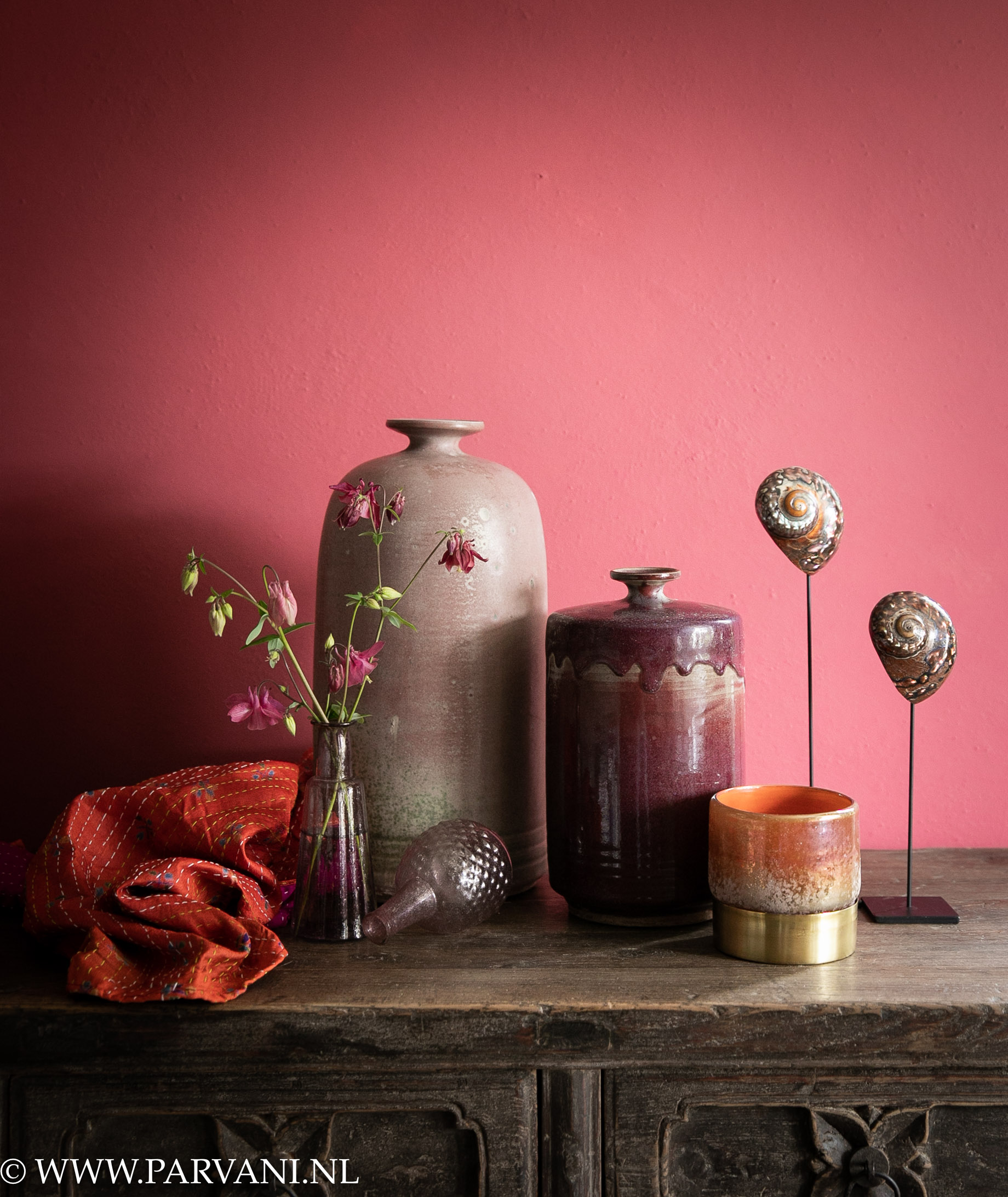 Aardewerk kruiken, glazen vaasjes, schelpen en waxglas in warme roze, oranje paarse kleuren