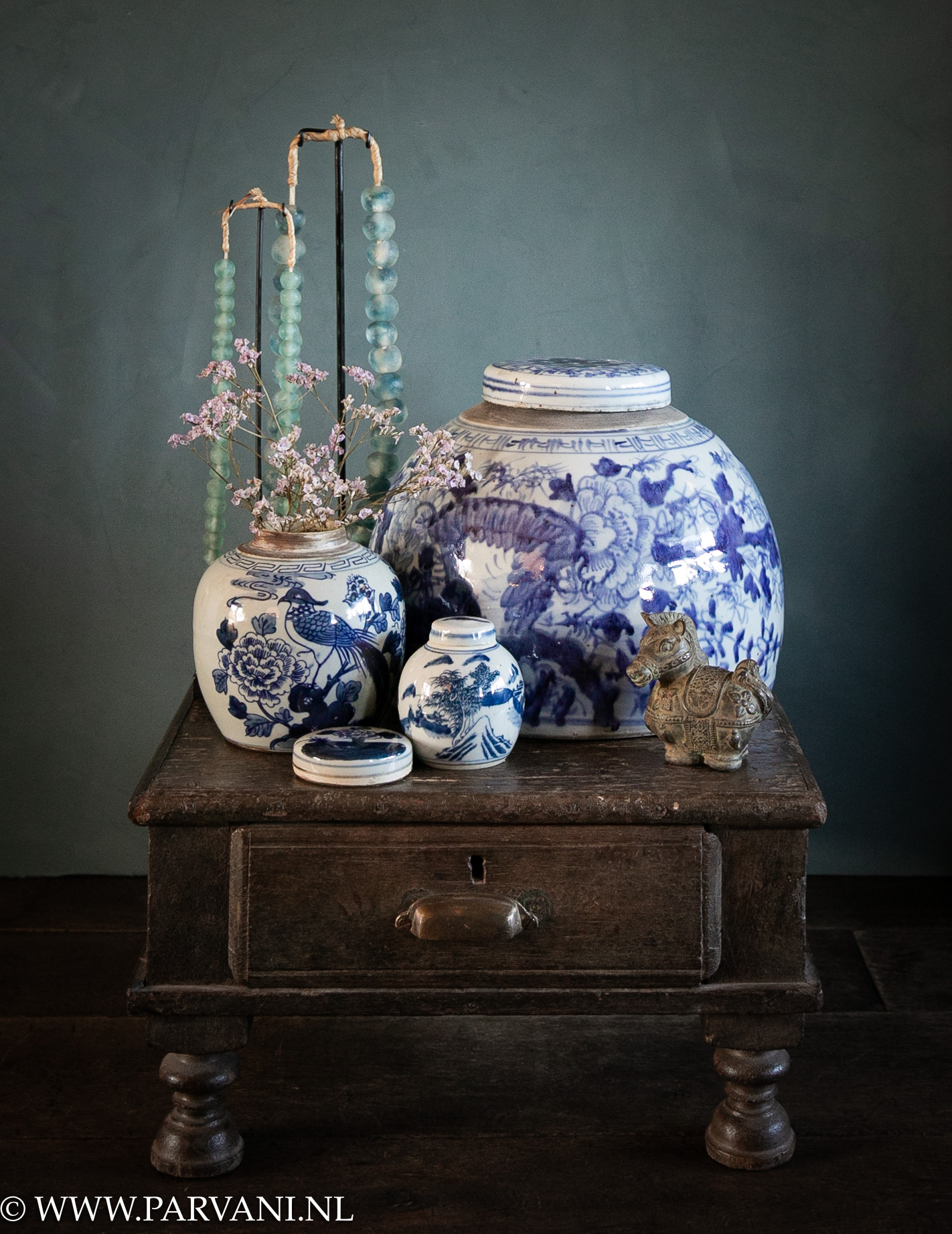 Chinese blauw wit beschilderde gemberpotten op oud Indiaas bajot tafeltje met bronzen paardje en blauw groene glaskettingen op standaard
