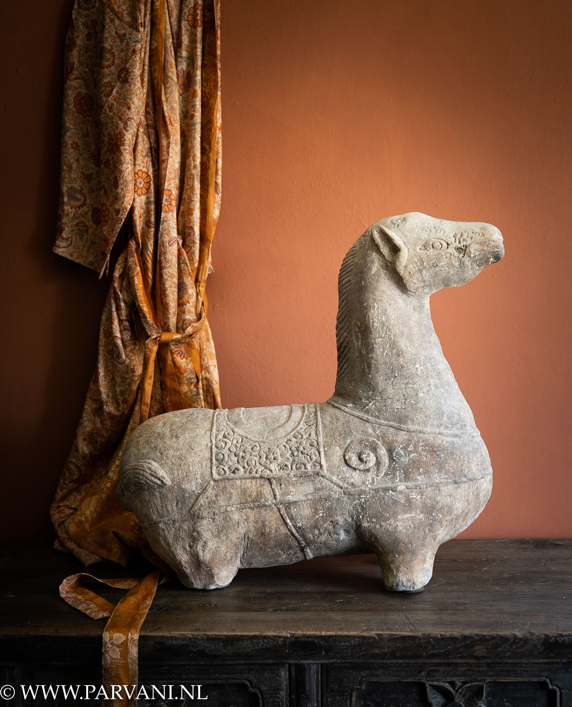 Groot uniek oud zandstenen paard uit Indonesië met terracotta kalkverf muur en zijde kimono