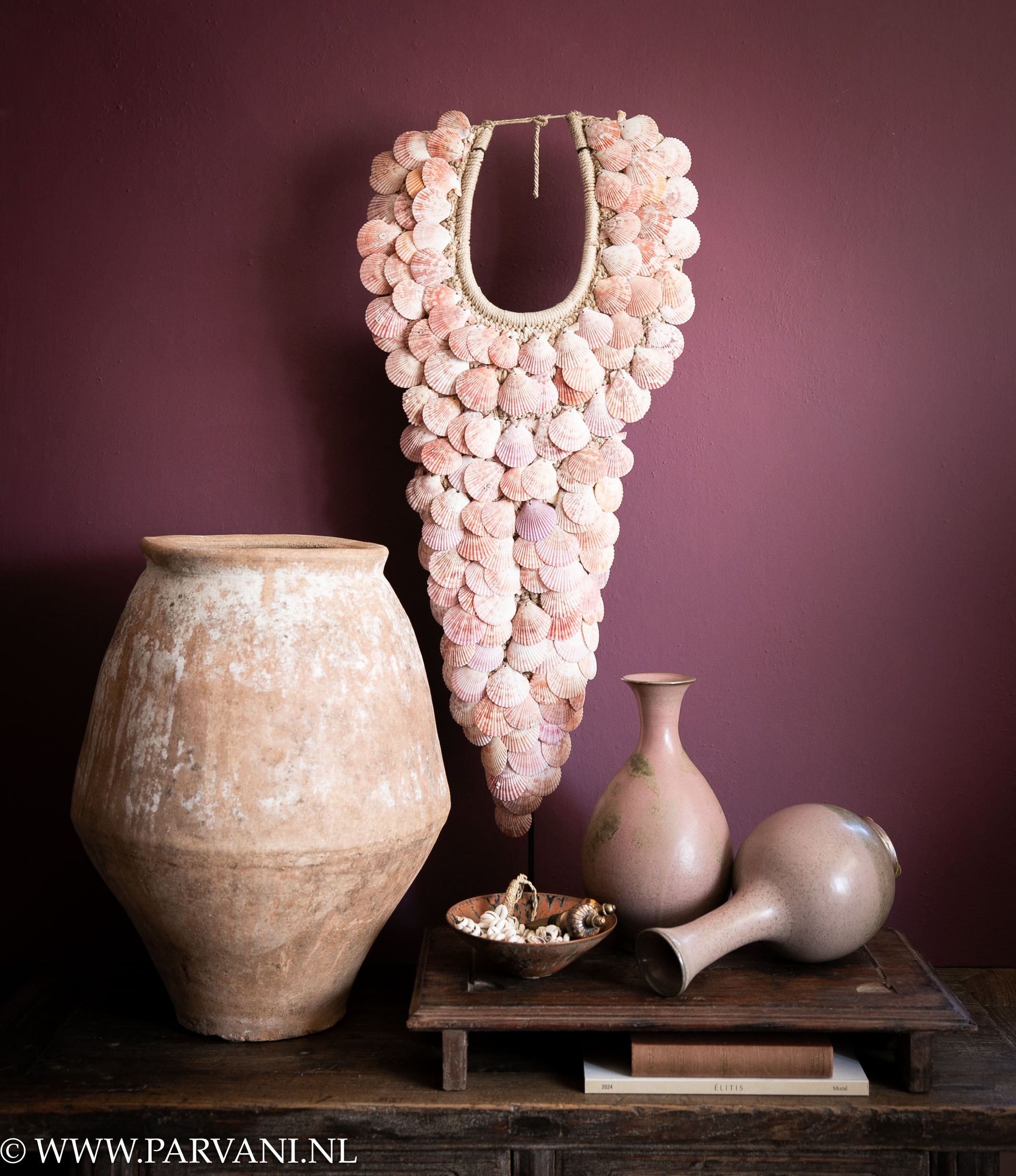 Ketting op standaard met roze oranje schelpen, grote terracotta pot en oud roze aardewerk vaasjes op houten bajot