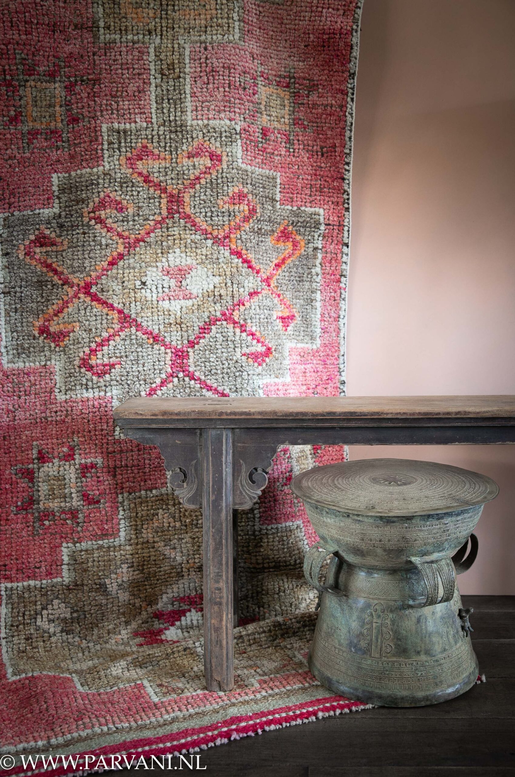 Kleurrijke vintage loper kelim runner in roze met groene kleuren en met oud houten bankje en bronzen drum