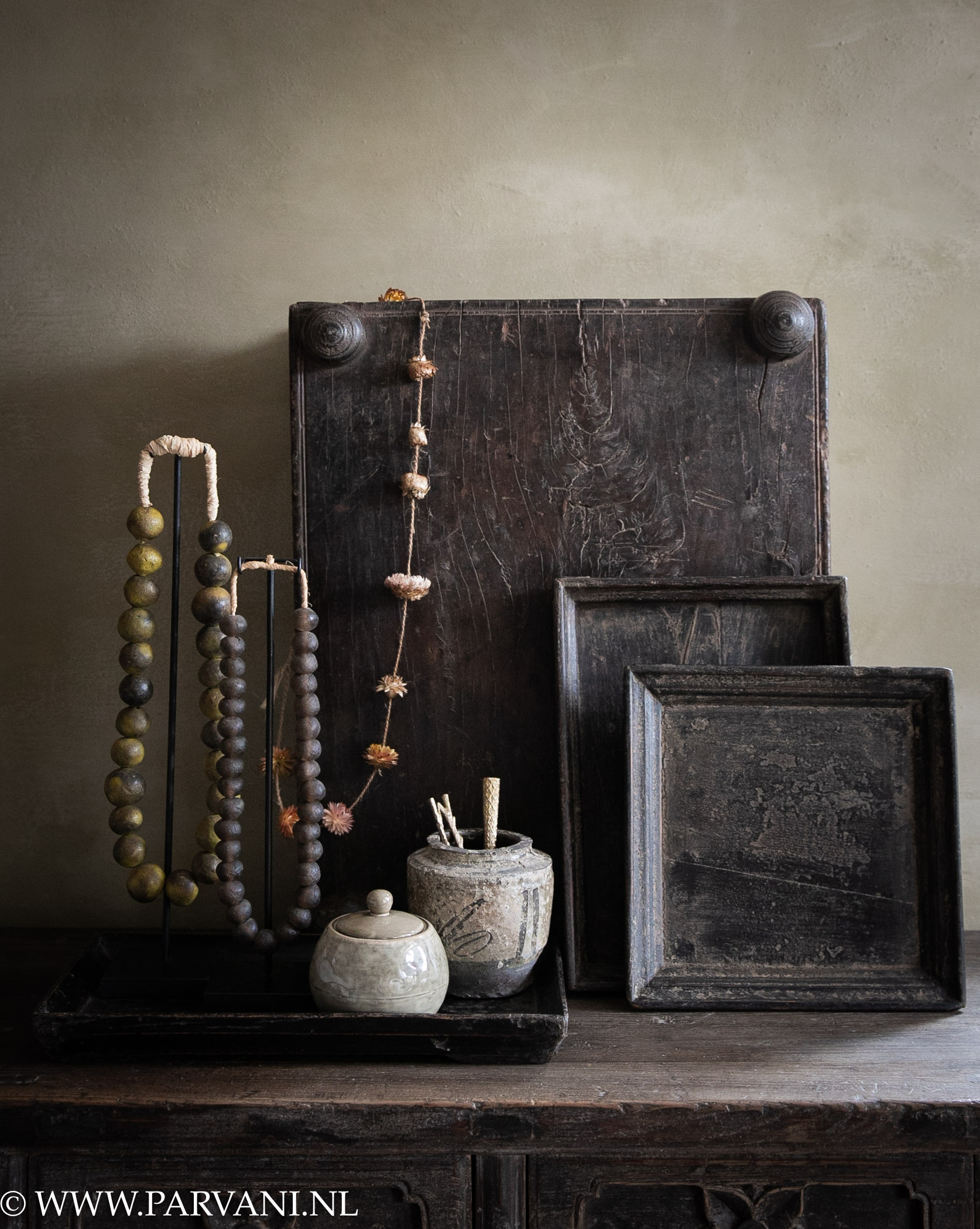 Oud uniek Indiaas bajot tafeltje met houten dienbladen uit China in donkerbruin zwarte kleur met kralenkettingen op standaard