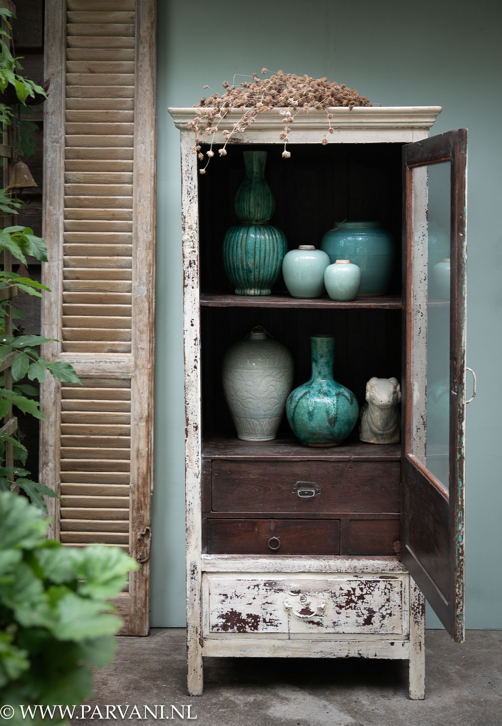 Smal oud houten vitrinekastje glaskast uit India met donkere binnenzijde en creme kleurige buitenkant met blauw groene vazen