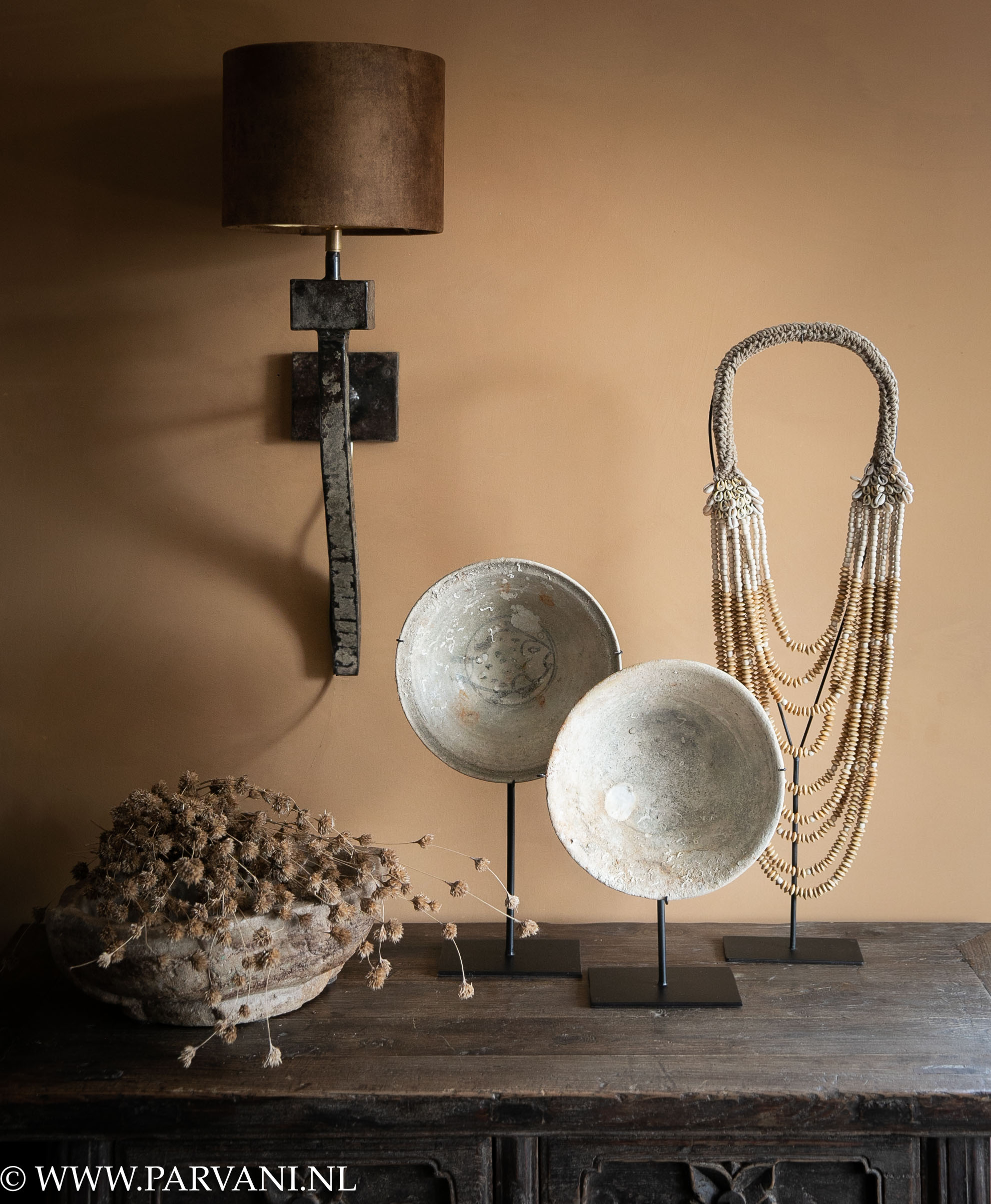 Stoere bruin metalen wandlamp met vintage velvet kap in goudbruine kleur met stenen schalen en kralenketting op standaard