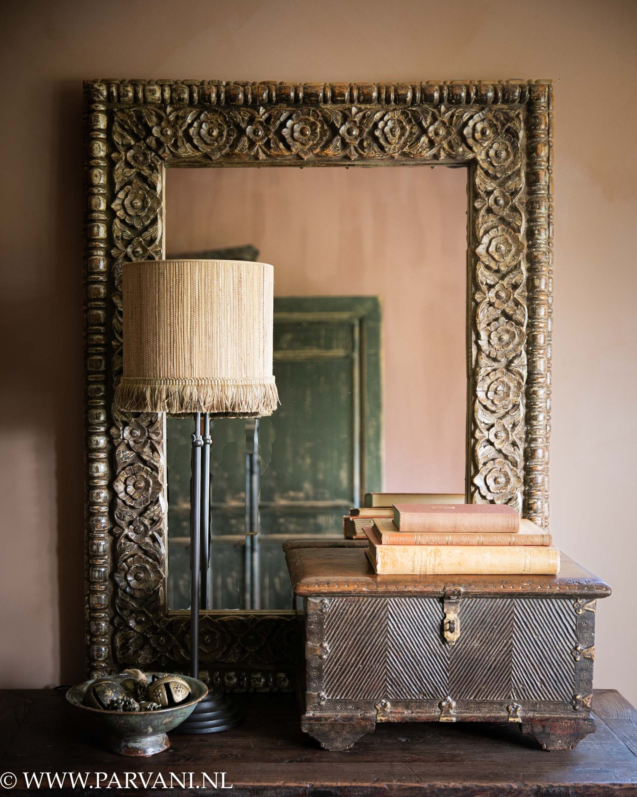 Unieke spiegel uit India met houten lijst met snijwerk en oud houten kistje met ijzerbeslag en tafellamp Delphi met naturel kleurige lampenkap met franjes