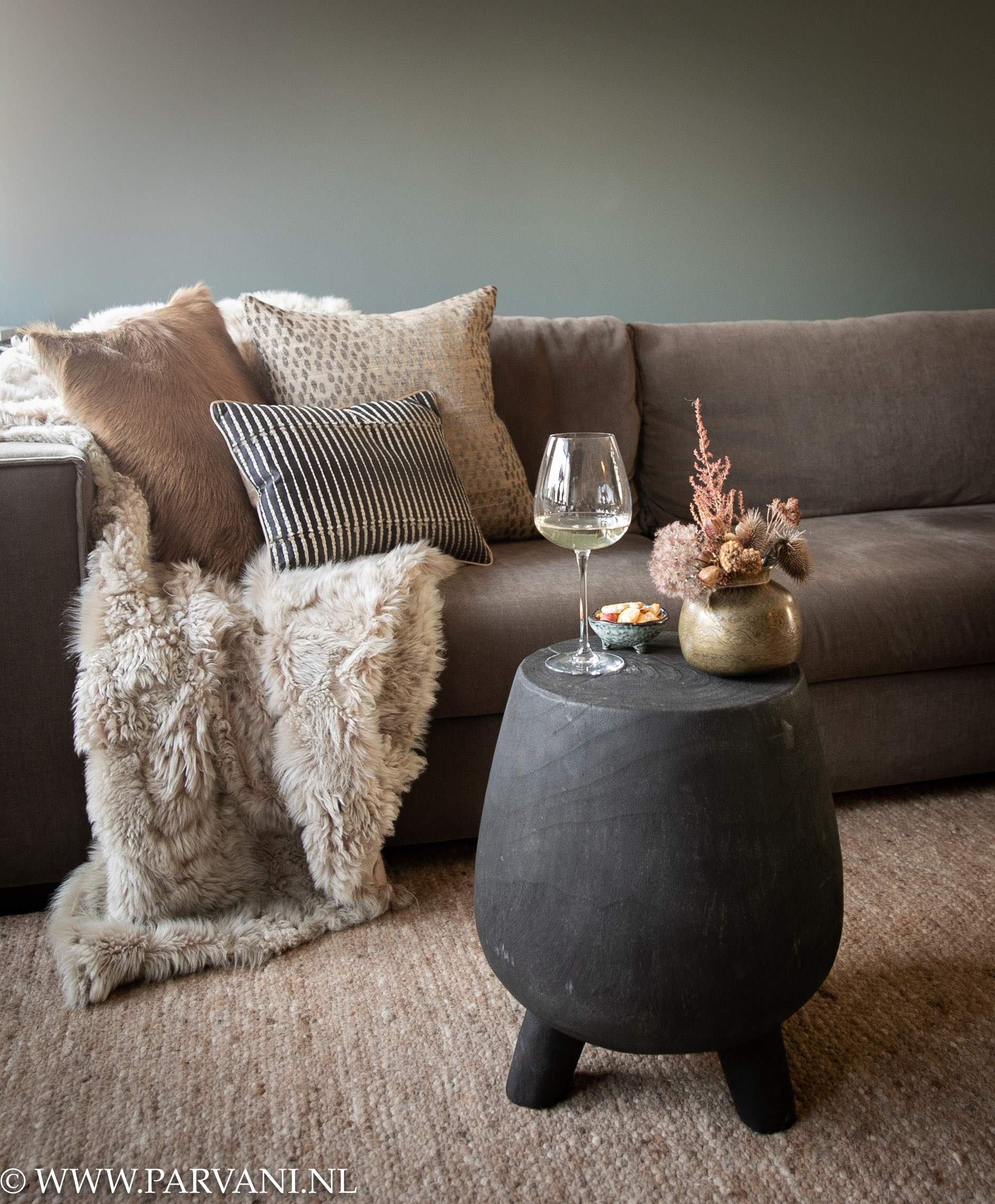 Klein rond donkerbruin zwart houten bijzettafeltje op pootjes bij bank