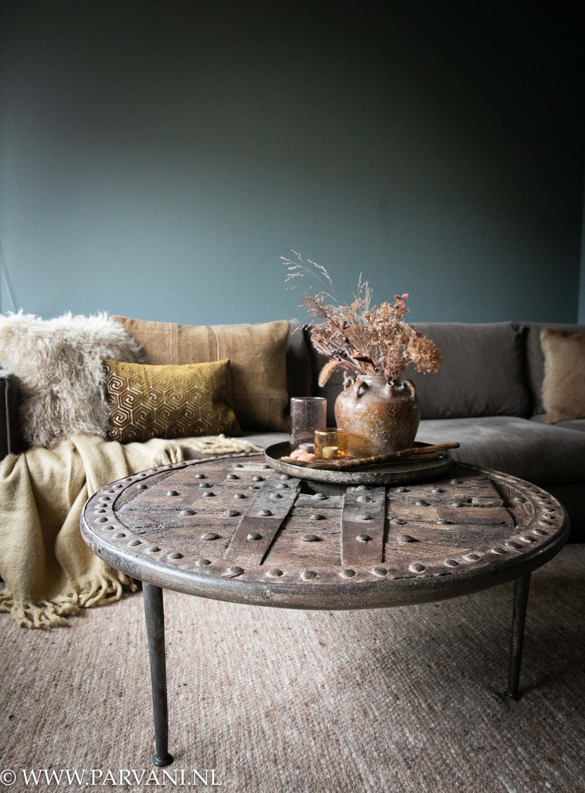 Grote ronde salontafel gemaakt van een stoer oud houten wiel met metalen rand en smeedijzeren beslag en poot