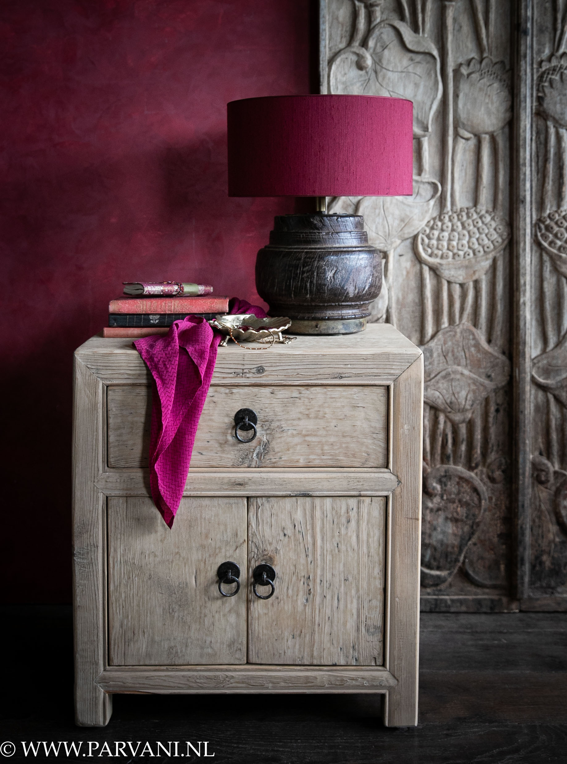 Set oude houten nachtkastjes in lichte naturelle kleur met 2 deurtjes en 1 lade en burgundy rode muur, houtsnijwerk paneel en schemerlamp met rood roze kap
