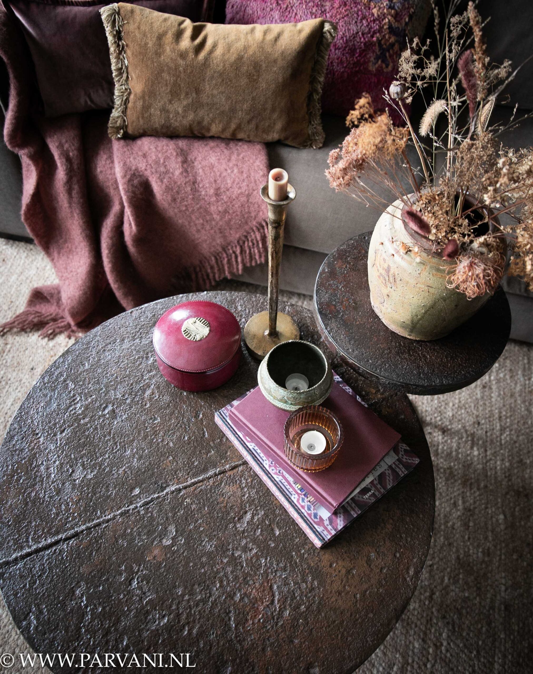 Stoere ronde roest bruine metalen salontafel met robuust blad en erbij een kleine hogere ijzeren bijzettafel