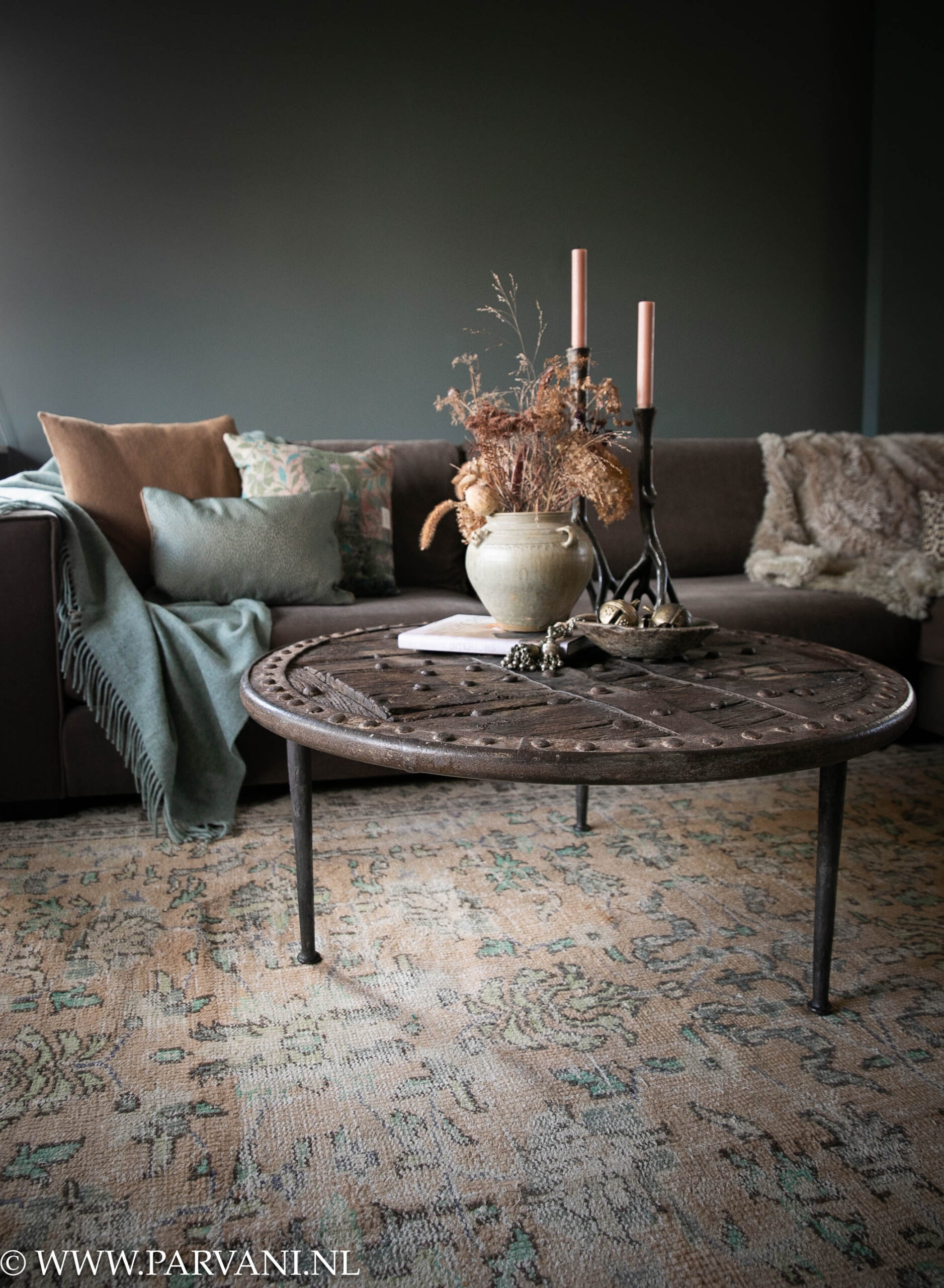 Vintage tapijt met mooi patroon in oranje terra kleur met accenten in groen, turquoise en ronde oude wieltafel