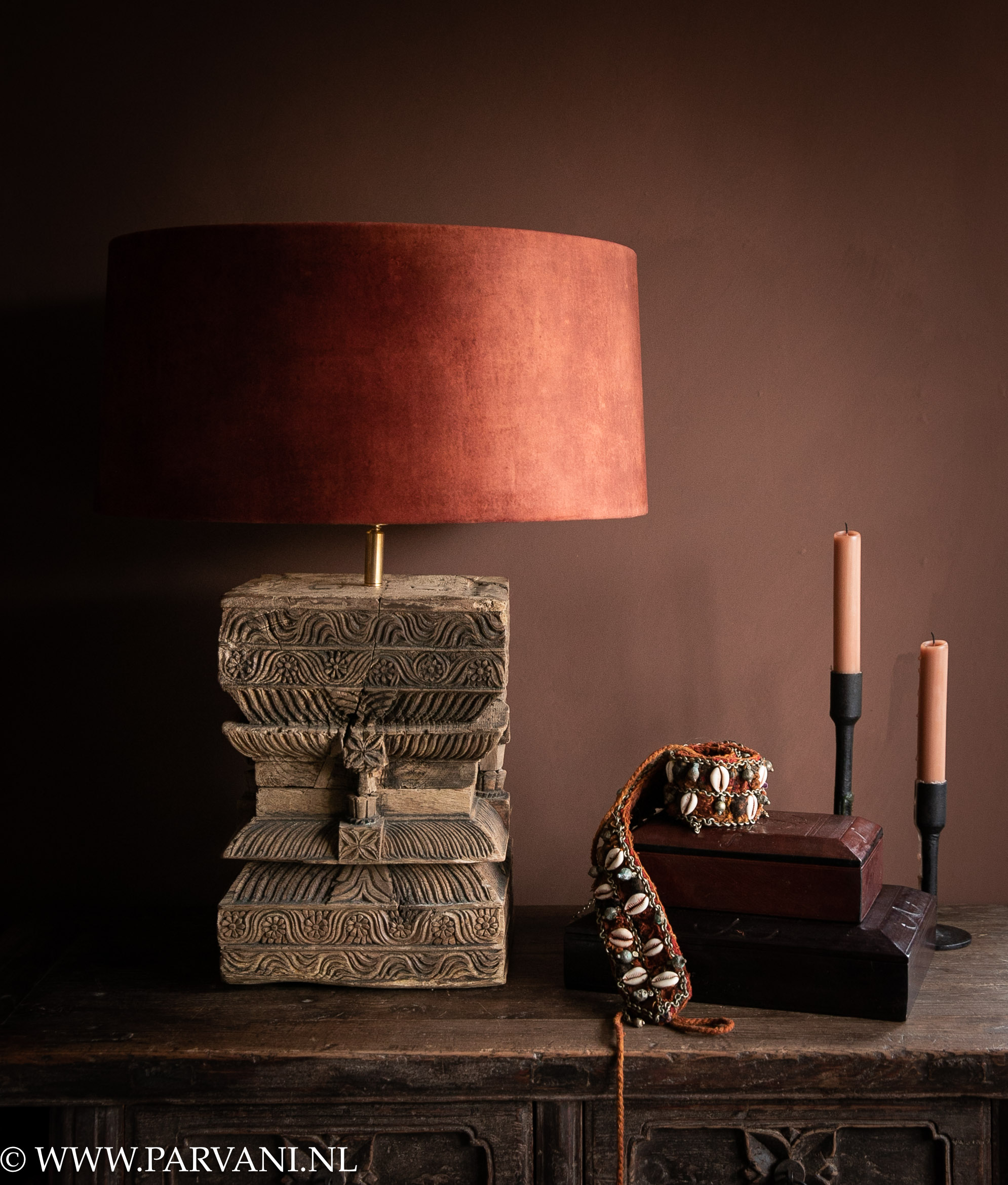 Indiase tafellamp met houtsnijwerk en terra rode velvet lampenkap met kistjes van leer en metalen kandelaars