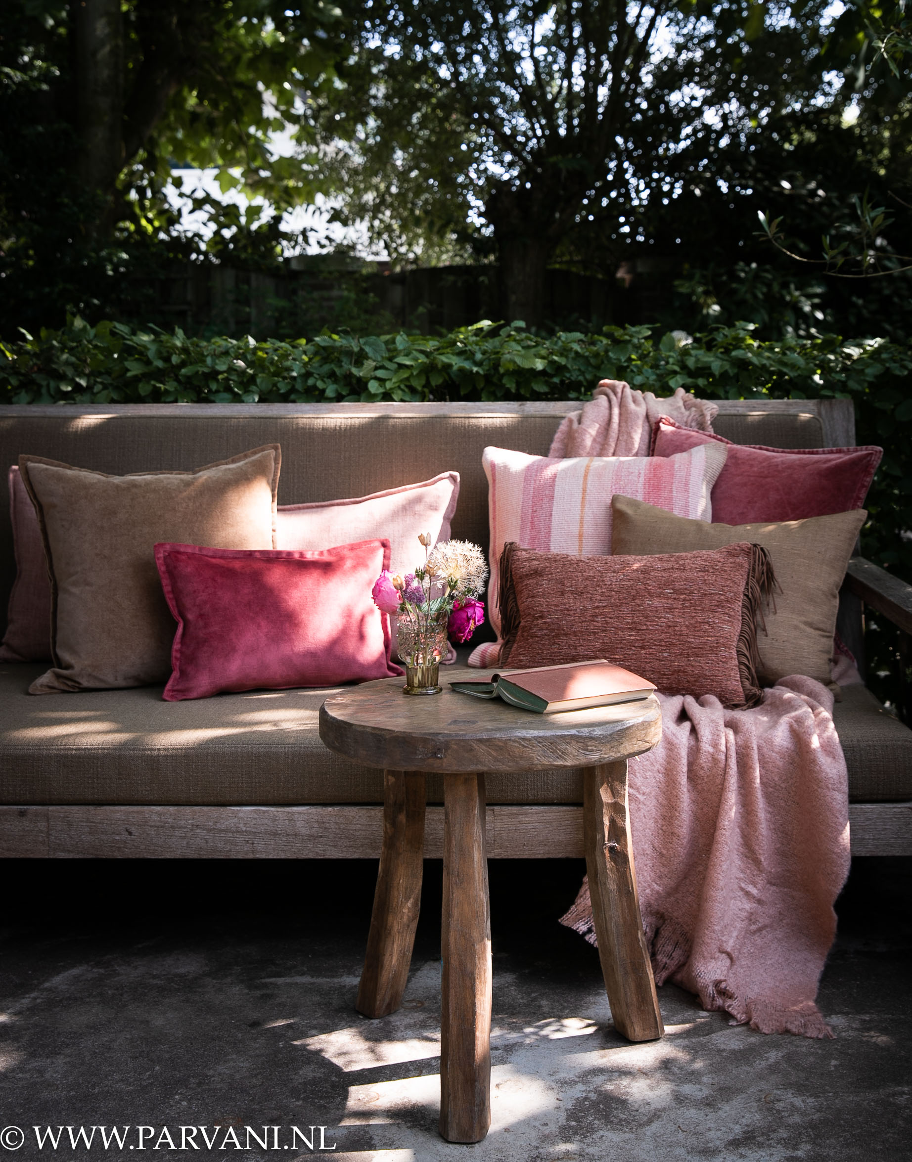 Kussens op loungebank tuinbank in warme roze bruin beige en burgundy kleuren met kelim, velvet en mooie patroon kussens met oudroze plaid