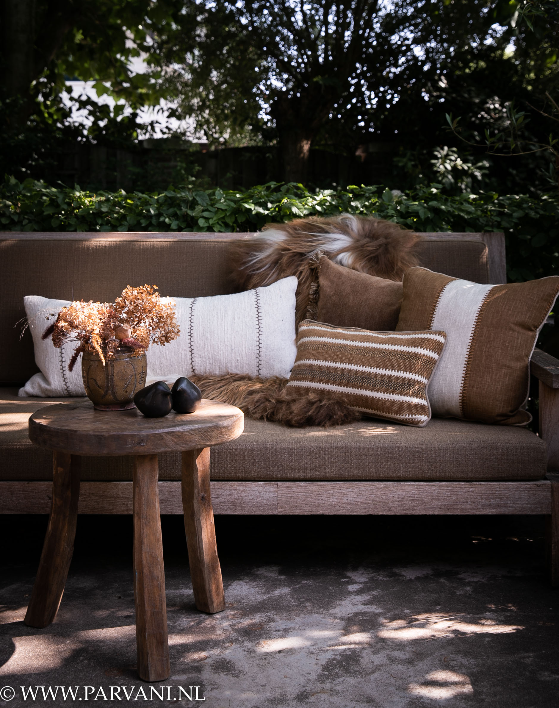 Loungebank met kussens in warme bruin en wit beige tinten met grote langharige Ijslandse schapenvacht