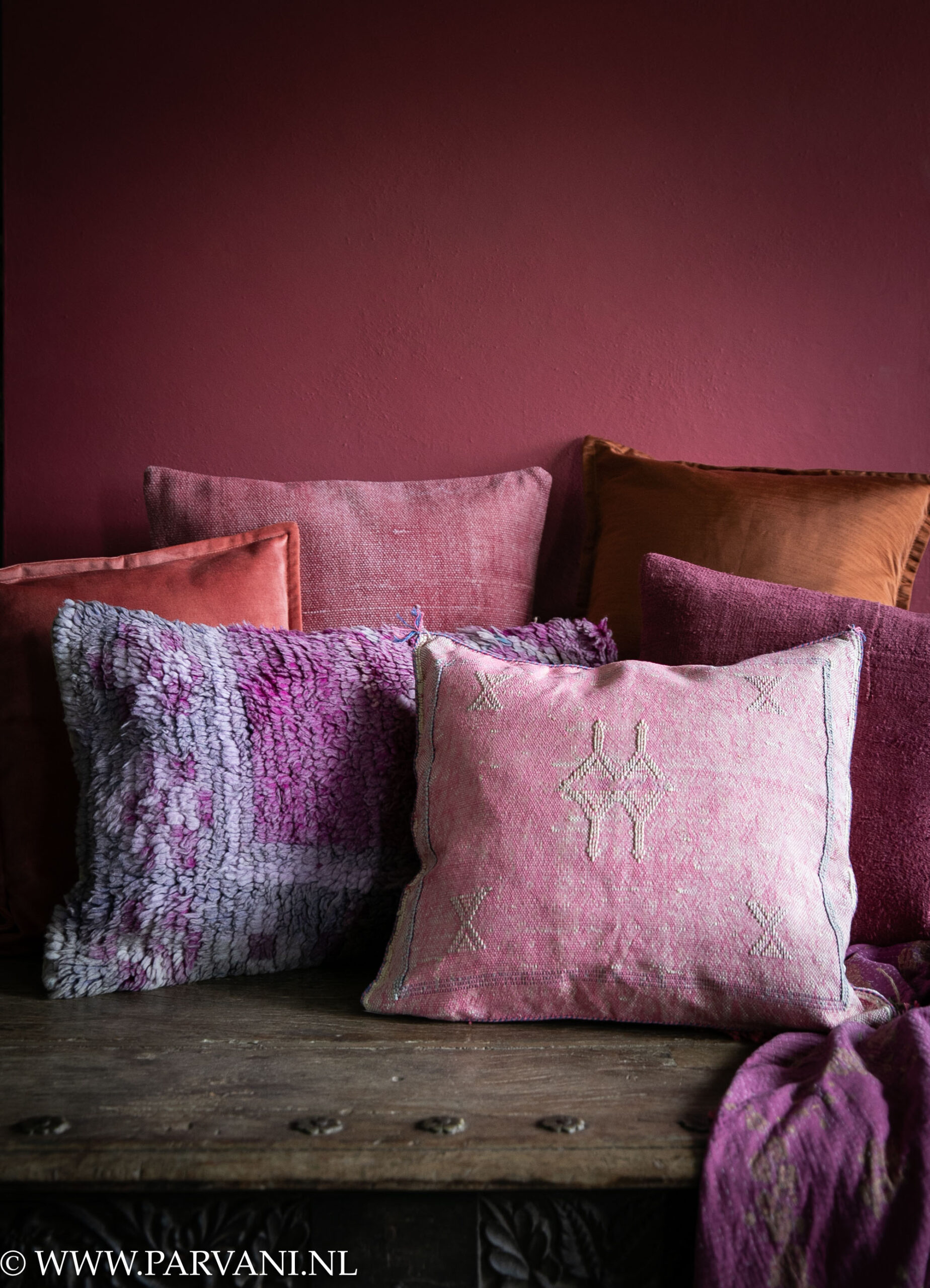 Mix kleurrijke kussens en plaid in warme cyclaam, roze, terra, oranje en paarse tinten