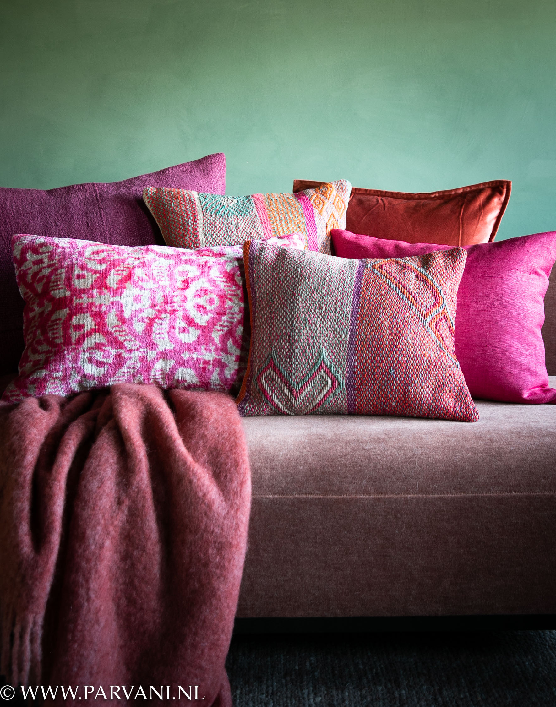 Mix kleurrijke sierkussens en mohair plaid in warme kleuren oranje, felroze, cyclaam en paars, met ikat, boliviaans, zijde en hennep