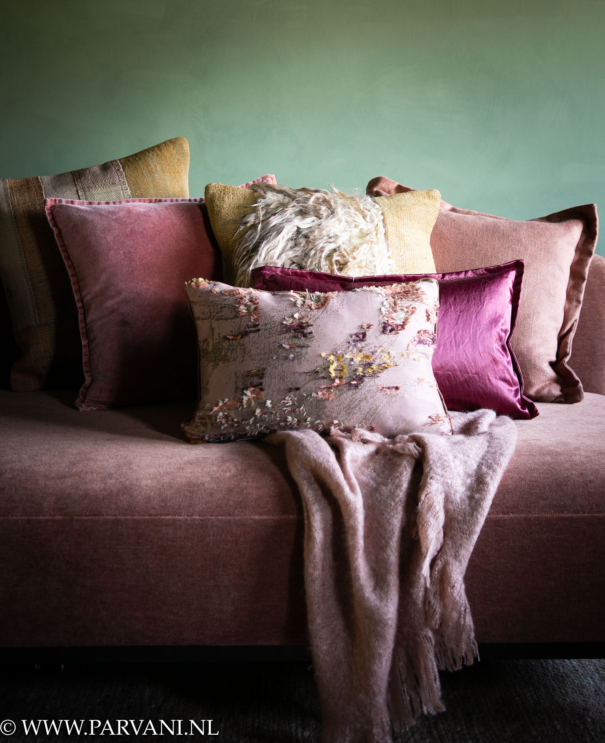 Mix kussens en plaid in warme kleuren roze, oudroze, cyclaam, brique, terra en warm geel met kelim, vacht, velvet, glans en linnen met patroon op bank Jan