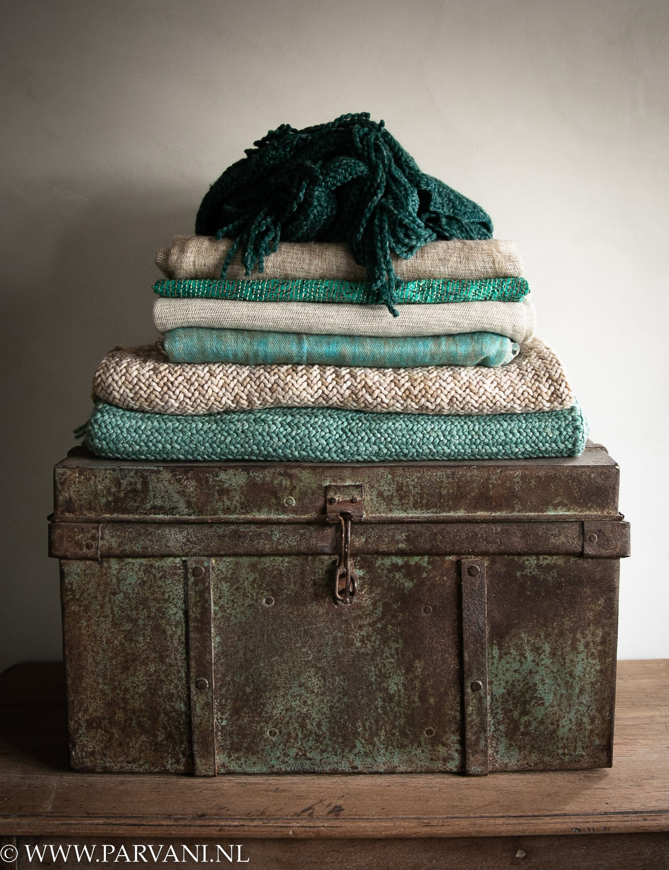 Oude Indiase metalen koffer met fair trade omslagdoeken poncho's Manos del Uruguay en yakwollen sjaals in groen turquoise tinten