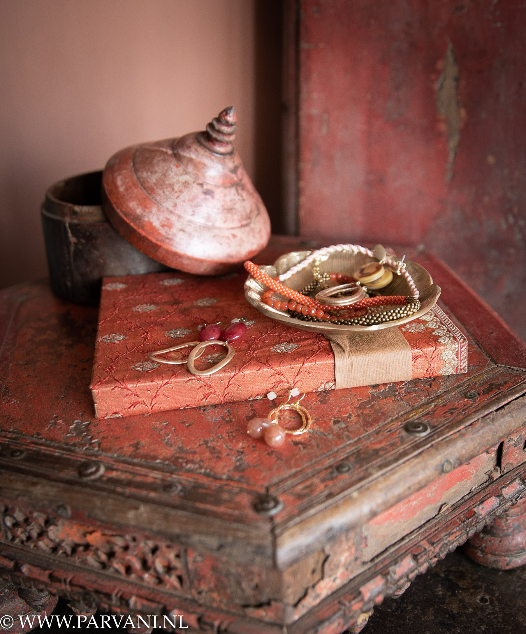 Sieraden A Beautiful Story in rood oranje kleuren op oud Indiaas bajot tafeltje