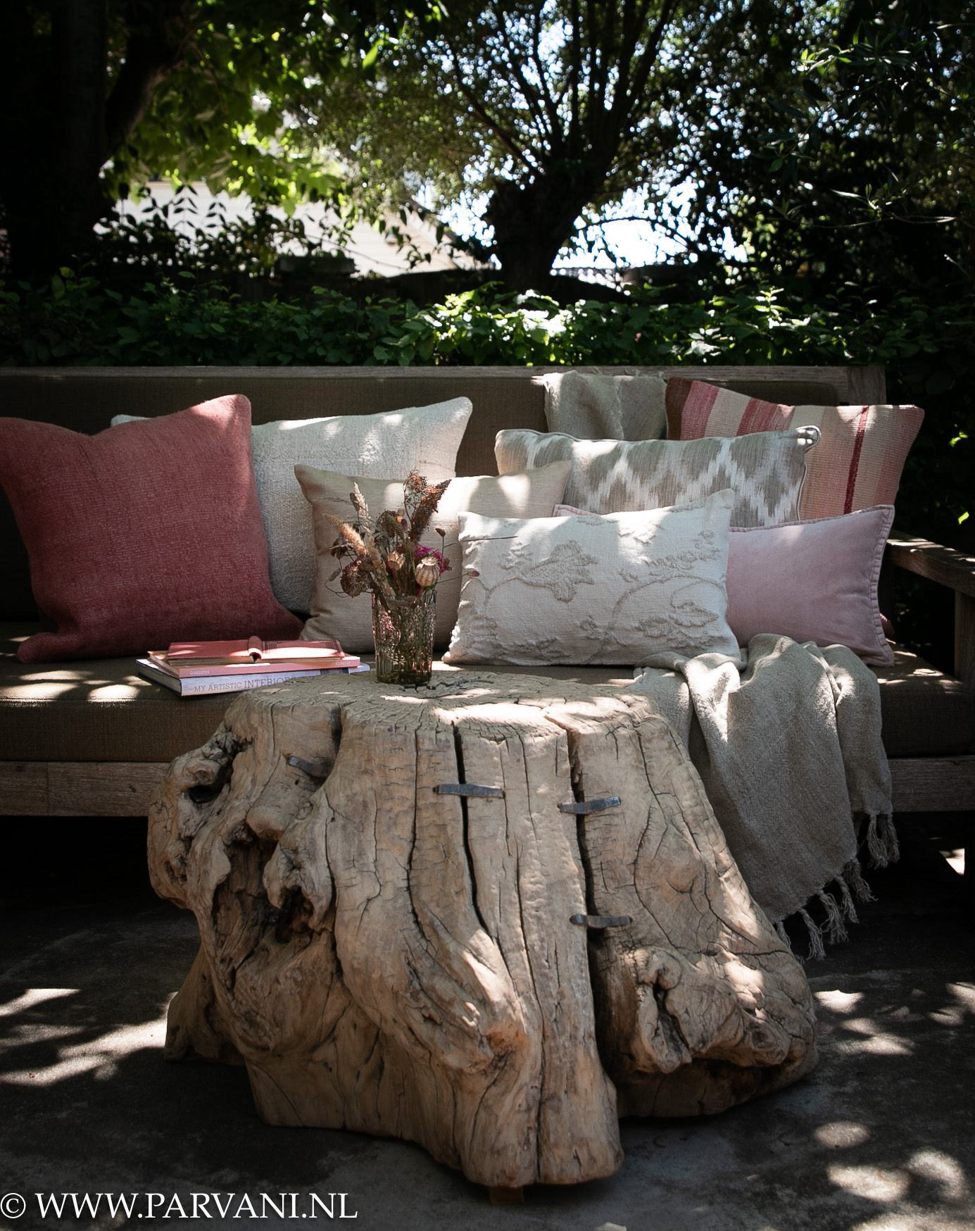 Tuinbank met kussens en plaid in lichte beige naturelle kleuren met kelim linnen velvet en patroon kussens in roze rode tinten