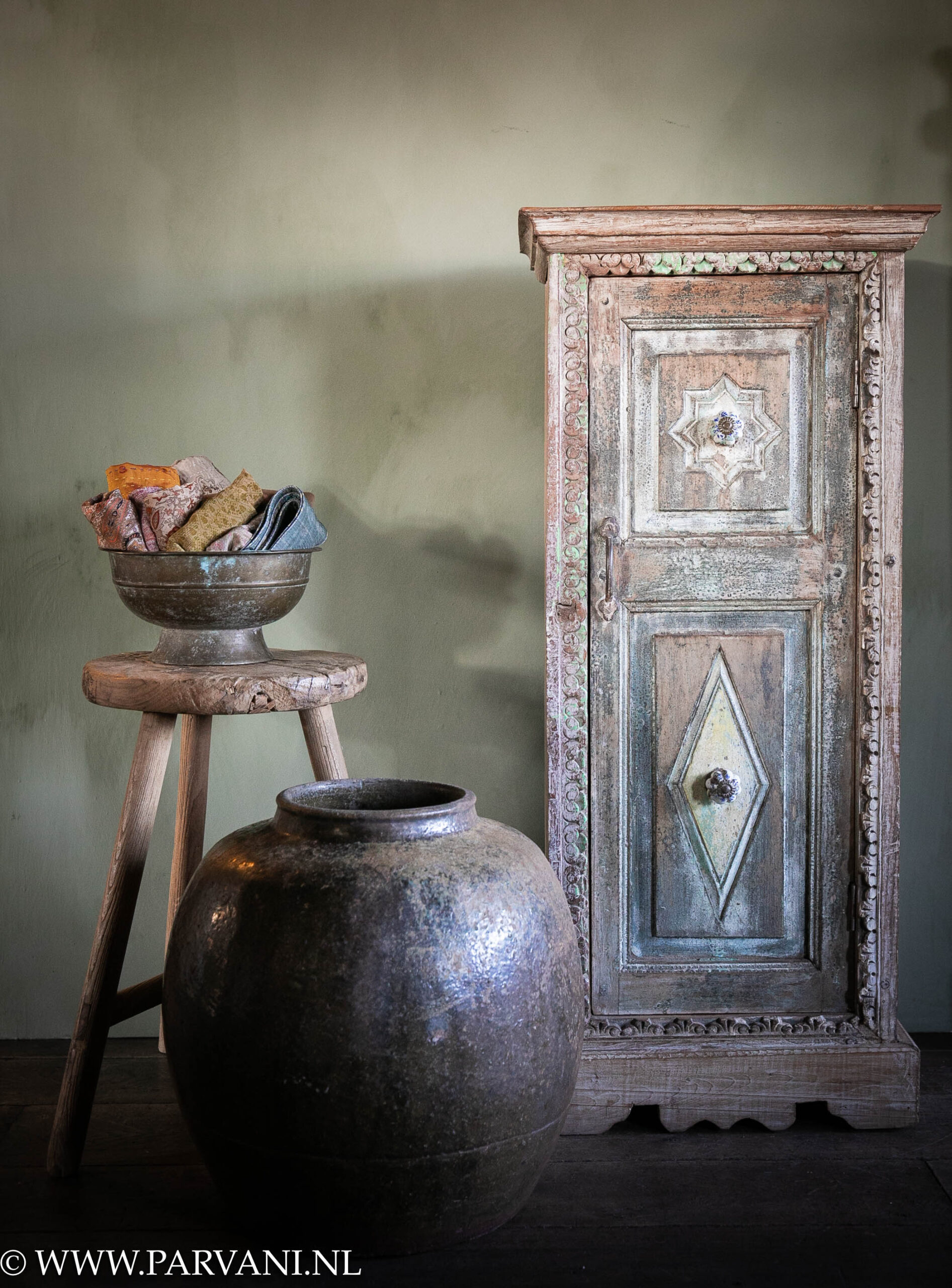 Hoog smal uniek Indiaas kastje met snijwerk, blauw groene patina en oud houten krukje met schaal en grote aardewerk pot