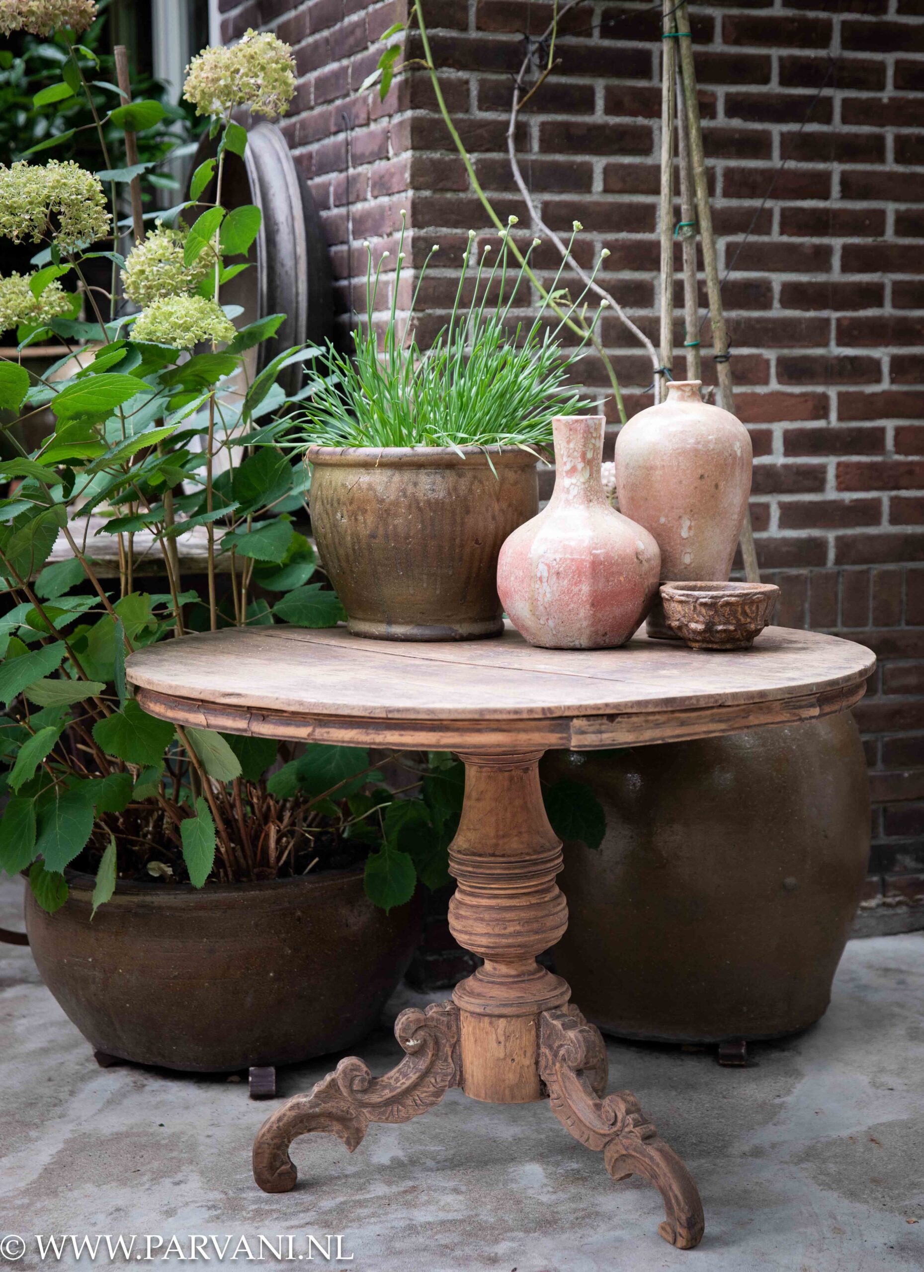 Grote oude houten wijntafel, hoge ronde bijzettafel uit Indonesië met mooie poot en oud roze vazen