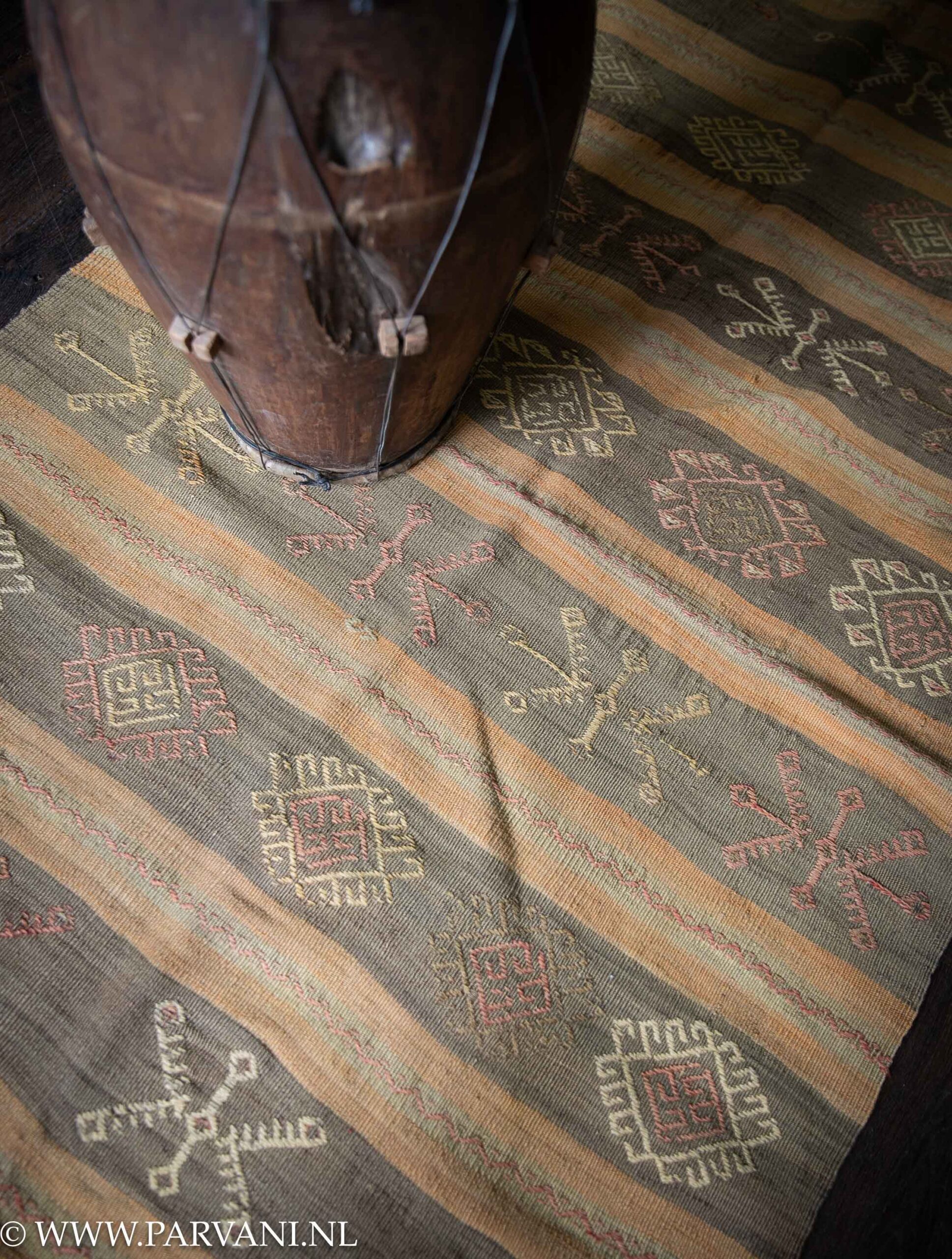 Huisdieren Weekendtas tijdschrift Klein formaat kelim tapijt vloerkleed met mooie kleuren en patroon in oker  geel groen en terra roze en erop een oude houten trom bijzettafel | Parvani